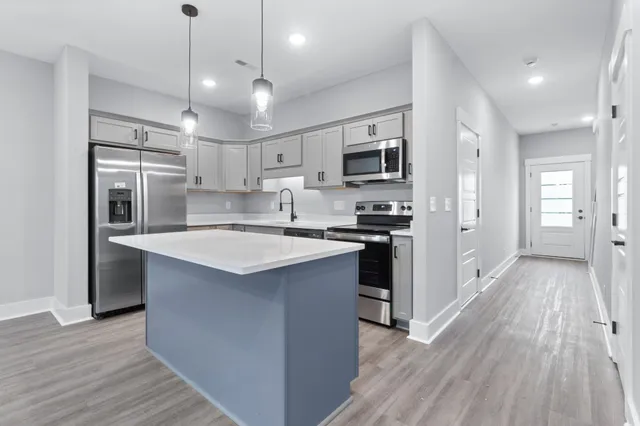 a kitchen with a sink dishwasher a stove top oven a refrigerator with island and cabinets