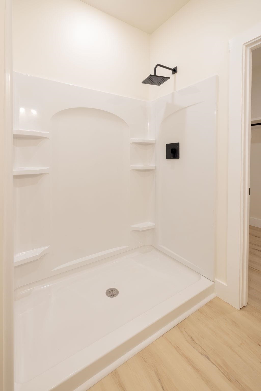 37 William Teague Lane Ramer, TN 38367 - Photo 26 of 39 White shower stall featuring a matte black square rain showerhead, coordinated matte black trim, built-in shelving, and a floor drain