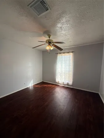 an empty room with wooden floor chandelier fan and windows