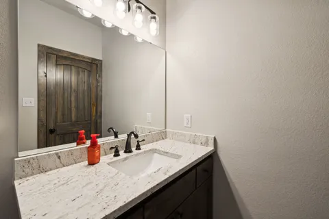 a bathroom with a granite countertop toilet sink and mirror