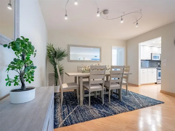 a kitchen with stainless steel appliances granite countertop a refrigerator a stove top oven and white cabinets with wooden floors