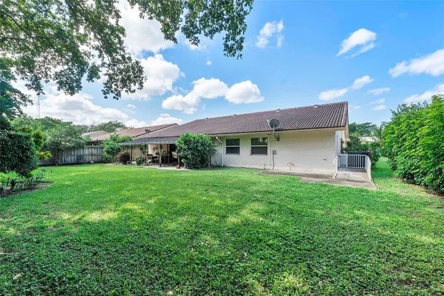 a backyard of a house with plants and large tree