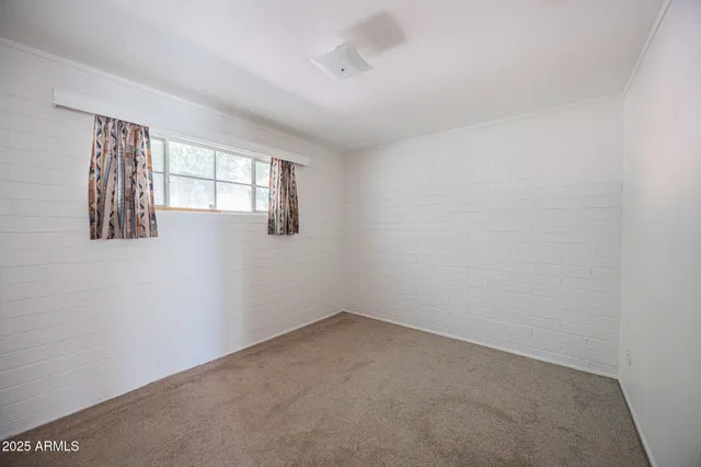 an empty room with windows and chandelier fan