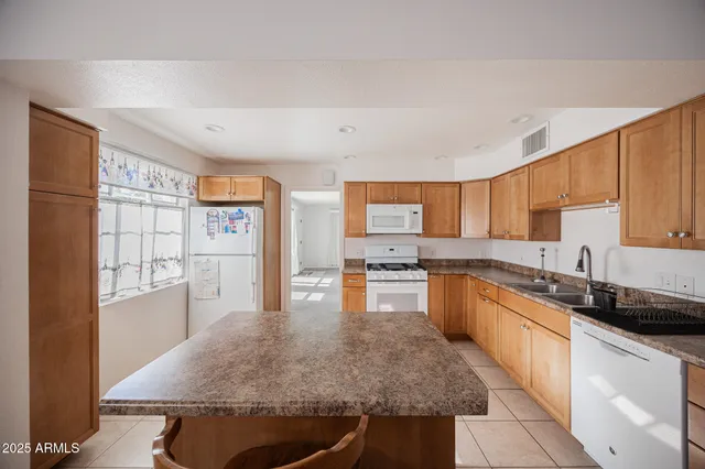 a kitchen with stainless steel appliances granite countertop a stove a sink dishwasher and a refrigerator with wooden cabinets