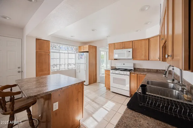 a kitchen with granite countertop a stove a sink dishwasher and a refrigerator with wooden floor