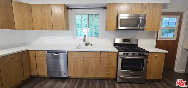 a kitchen with wooden cabinets a sink a stove and a refrigerator