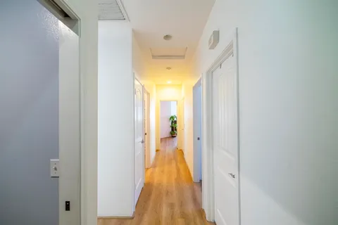 a view of a hallway with wooden floor and a bathroom