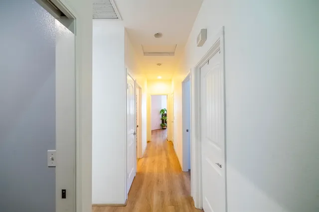 a view of a hallway with wooden floor and a bathroom