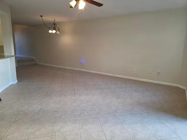 a view of an empty room with a chandelier fan