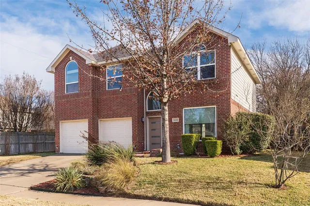 a view of a brick house with large windows and a tree