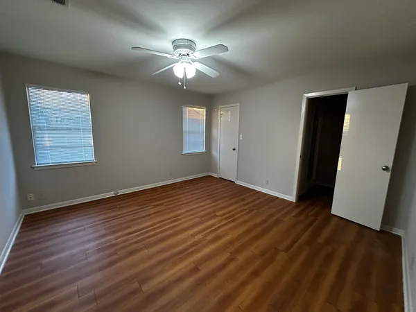 a view of an empty room with wooden floor and a window