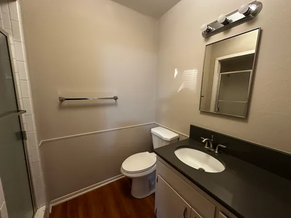 a bathroom with a granite countertop sink toilet and a mirror
