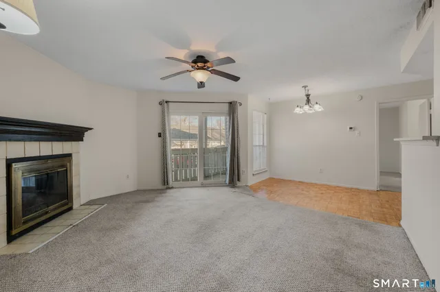 a view of an empty room with chandelier fan and fire place