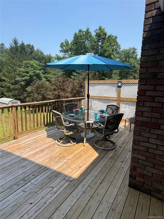 a view of a roof deck with table and chairs under an umbrella with wooden floor