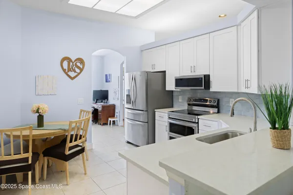 a kitchen with a refrigerator a stove a microwave a dining table and chairs with wooden floor