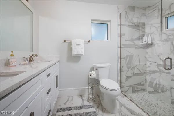 a bathroom with a granite countertop sink toilet and shower
