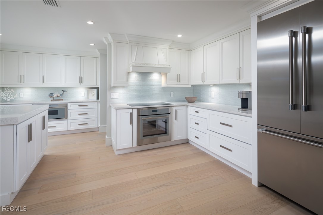 635 Fountainhead Lane Naples, FL 34103 - Photo 6 of 28 a kitchen with white cabinets stainless steel appliances and a refrigerator