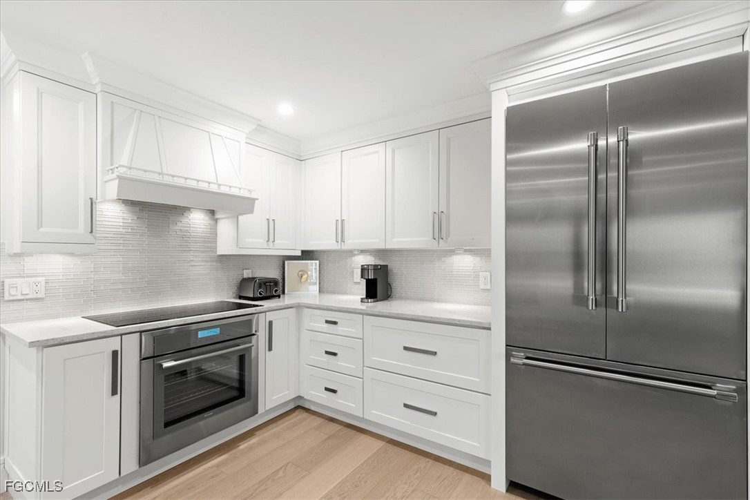 635 Fountainhead Lane Naples, FL 34103 - Photo 7 of 28 a kitchen with cabinets stainless steel appliances and wooden floor