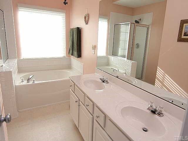 8333 Tie Stone Way Raleigh, NC 27613 - Photo 10 of 12 a bathroom with a double vanity sink a mirror and a bathtub