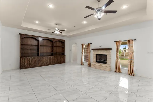 a view of a livingroom with a fireplace a chandelier fan and windows