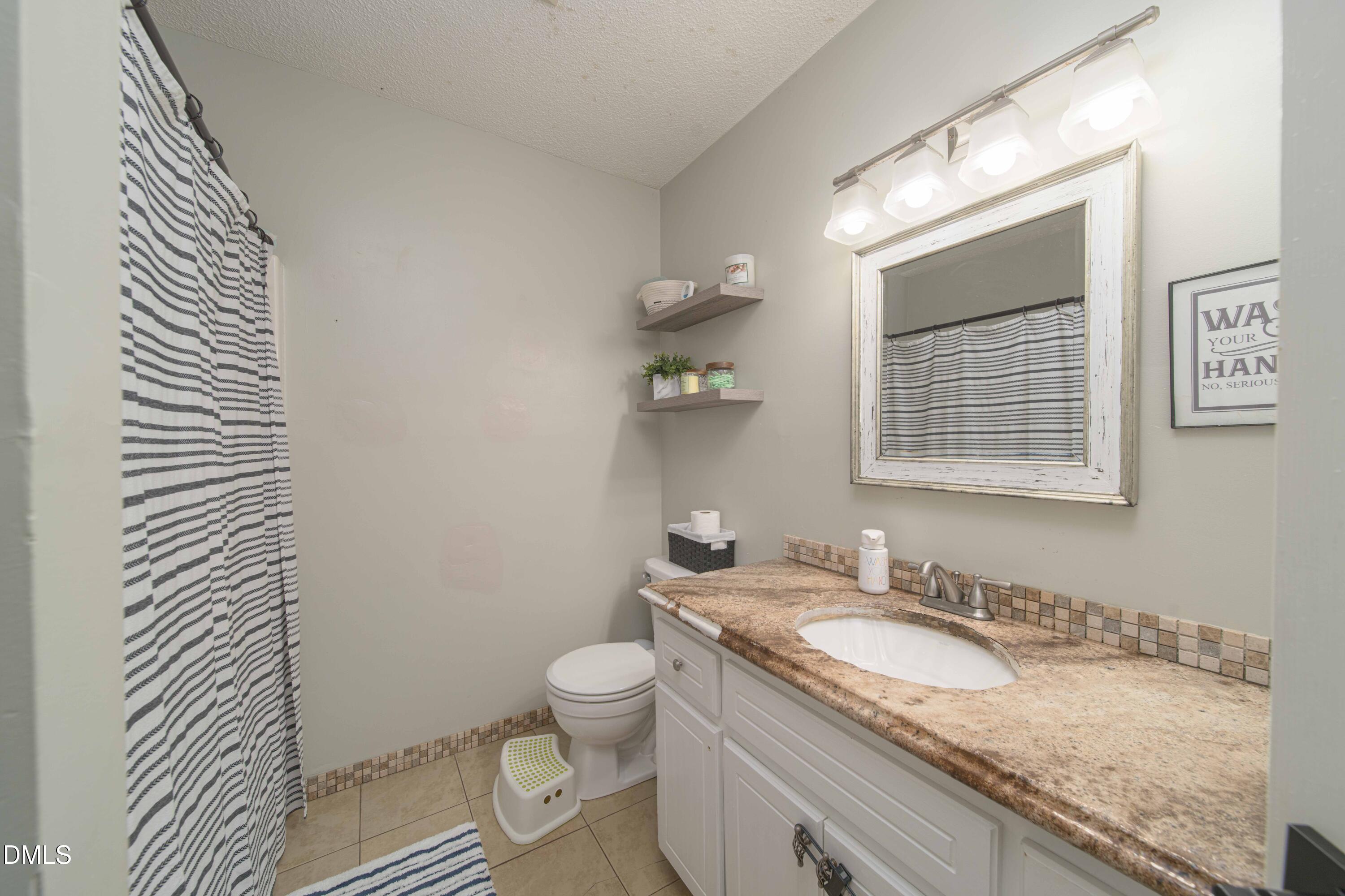 4411 Lessie Trail Rocky Mount, NC 27804 - Photo 18 of 27 a bathroom with a granite countertop sink toilet and mirror