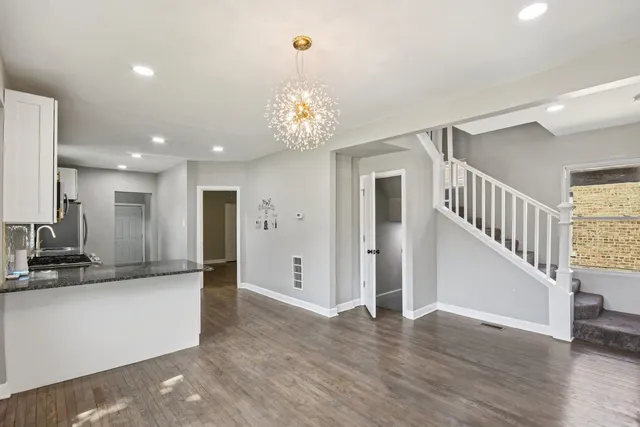 a view of a hallway with wooden floor and a kitchen