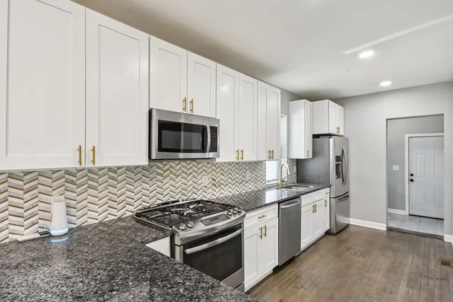 a kitchen with stainless steel appliances granite countertop a stove a sink and a microwave