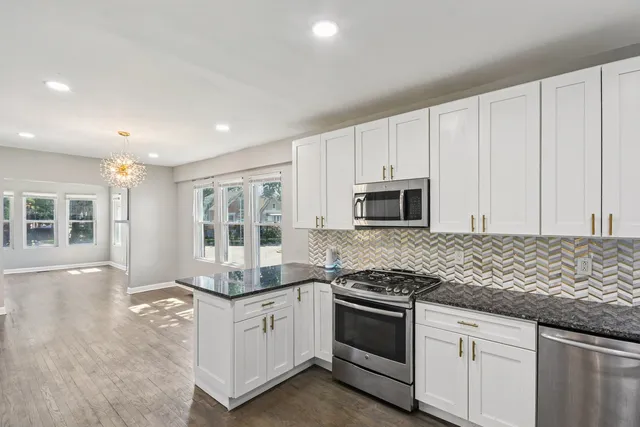 a kitchen with granite countertop white cabinets and stainless steel appliances