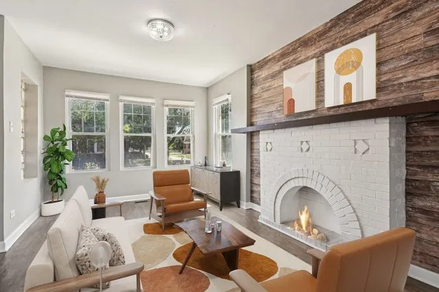a living room with furniture a fireplace and a large window