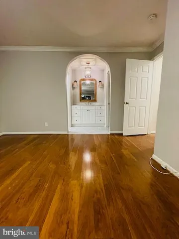 an empty room with wooden floor and fan