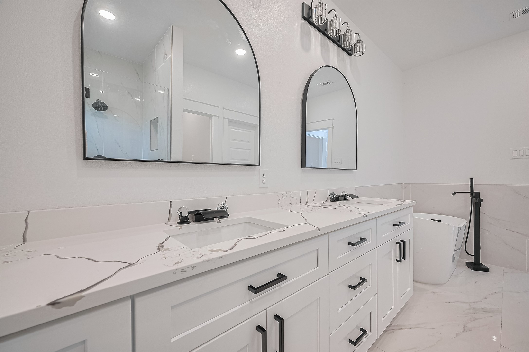 6747 Liverpool Street Houston, TX 77021 - Photo 9 of 18 The spa-like primary bathroom features a dual vanity, sleek white cabinetry, a freestanding soaking tub, and modern finishes for ultimate relaxation.