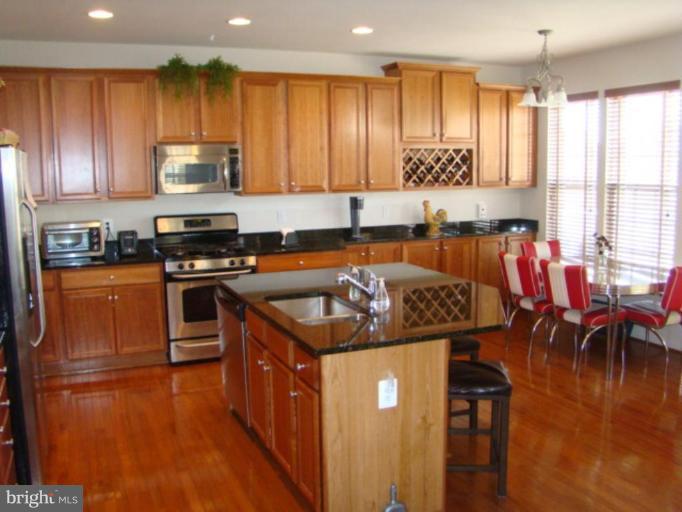 9204 Ribbon Falls Loop Bristow, VA 20136 - Photo 2 of 16 a kitchen with stainless steel appliances granite countertop a stove top oven a sink and a refrigerator