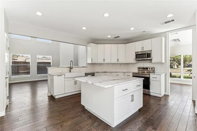 a kitchen with white cabinets and appliances