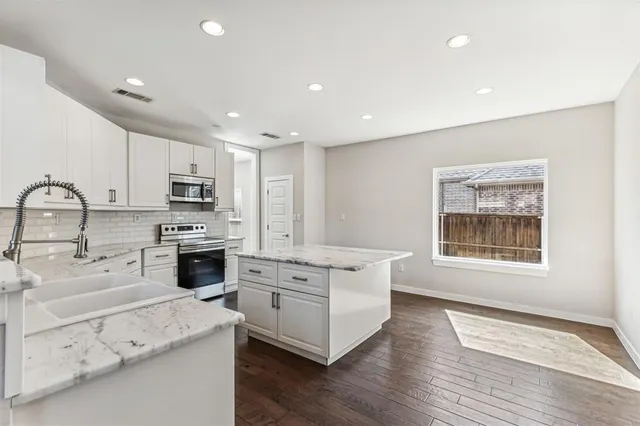 a kitchen with white cabinets appliances and wooden floor