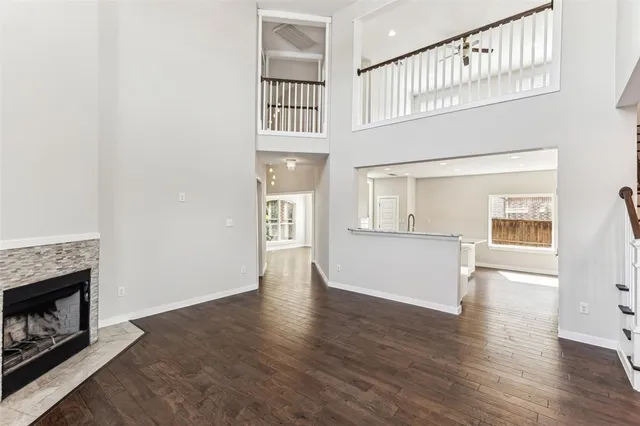 an empty room with wooden floor fireplace and windows