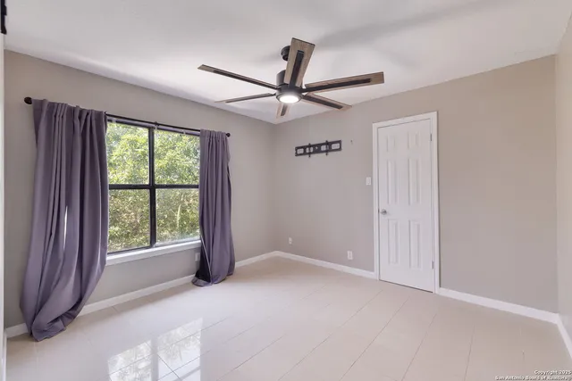 an empty room with windows and ceiling fan