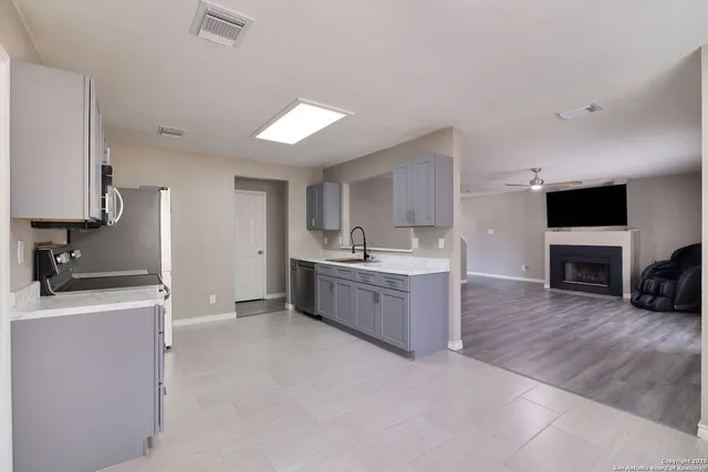 a large white kitchen with a sink a microwave a stove and refrigerator