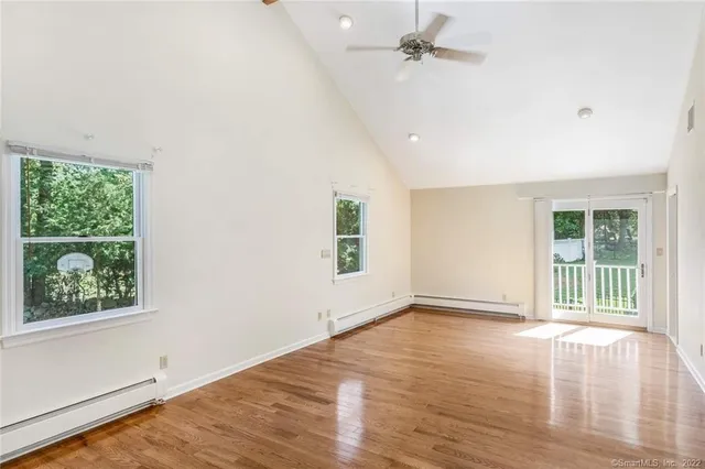 an empty room with wooden floor ceiling fan and windows