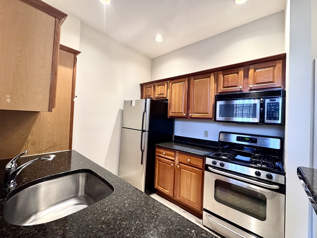 a kitchen with stainless steel appliances granite countertop a sink a stove and a refrigerator