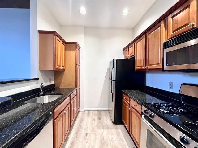 a kitchen with granite countertop stainless steel appliances a sink stove top oven and cabinets