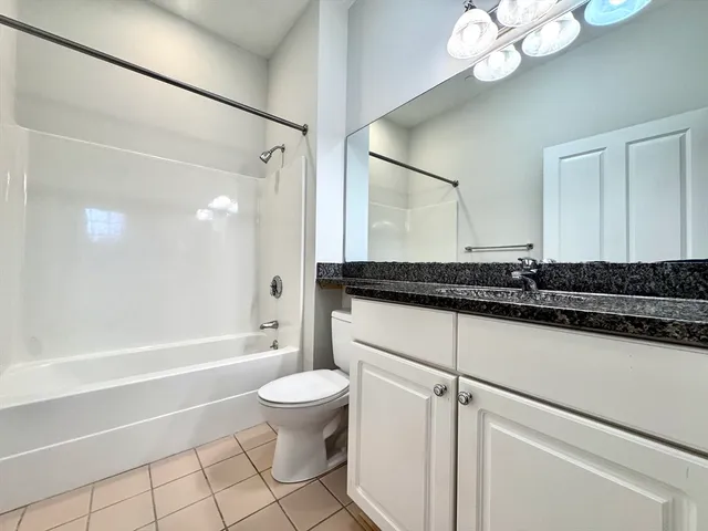 a bathroom with a granite countertop sink a toilet a mirror and bathtub