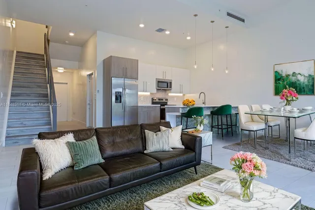 a living room with furniture kitchen and a potted plant