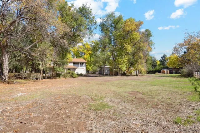 a view of a field with trees and a building