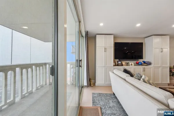 a living room with stainless steel appliances a flat screen tv and a view of kitchen