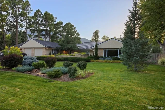 a backyard of a house with table and chairs under an umbrella