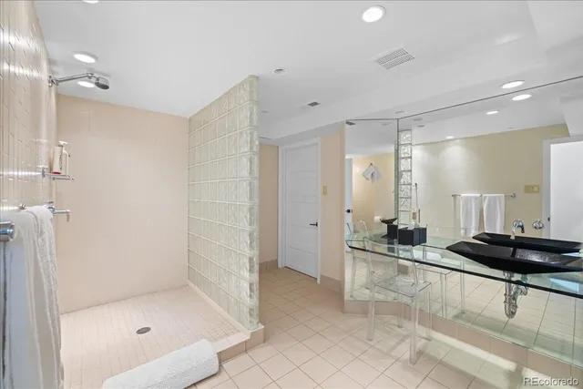 a bathroom with a glass shower door a sink and a mirror