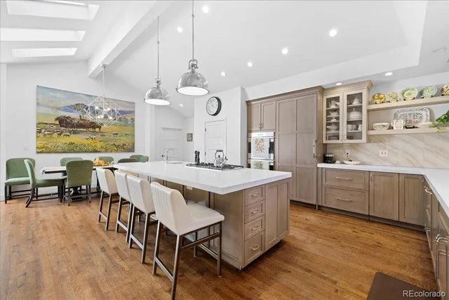 a kitchen with stainless steel appliances granite countertop a stove a sink a refrigerator and a dining table with wooden floor