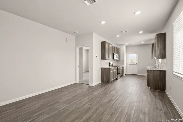 a large kitchen with a center island wooden floor stainless steel appliances and cabinets