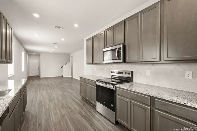 a kitchen with stainless steel appliances granite countertop a stove a sink and a microwave