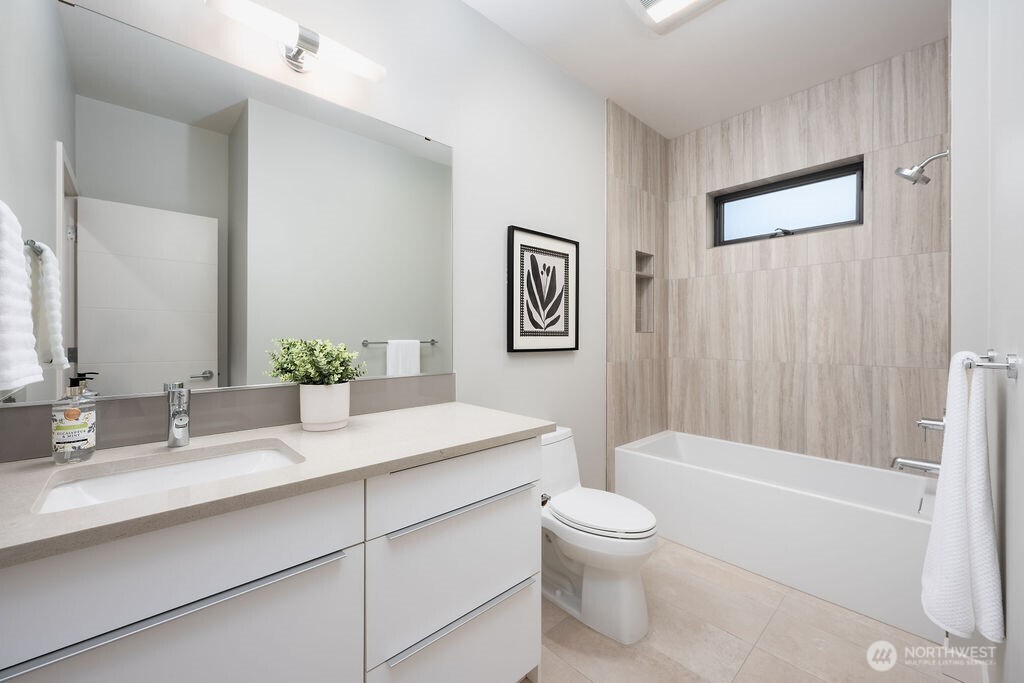 4815 Evanston Avenue North, Unit B Seattle, WA 98103 - Photo 32 of 37 a bathroom with a granite countertop sink a toilet and a bathtub
